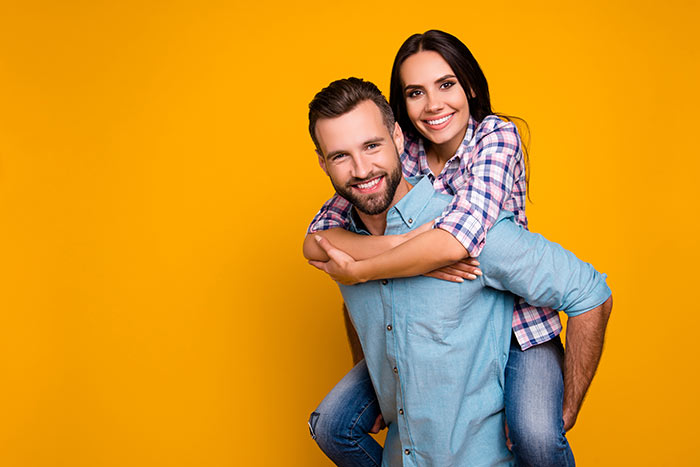 smiling couple posing in front orange background